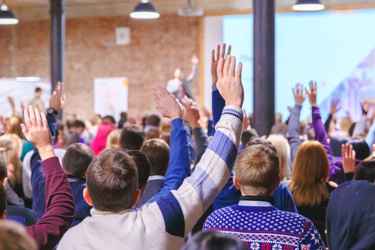 Muchos alumnos levantan la mano en un aula