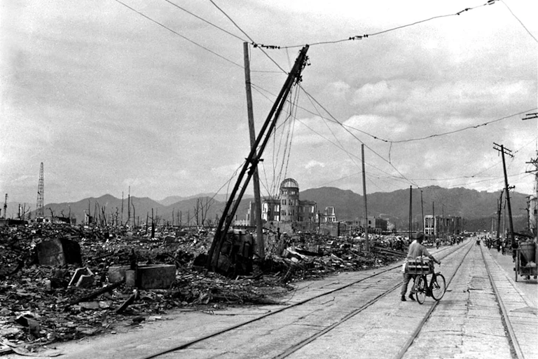 Man pushes bicycle in devastated city.