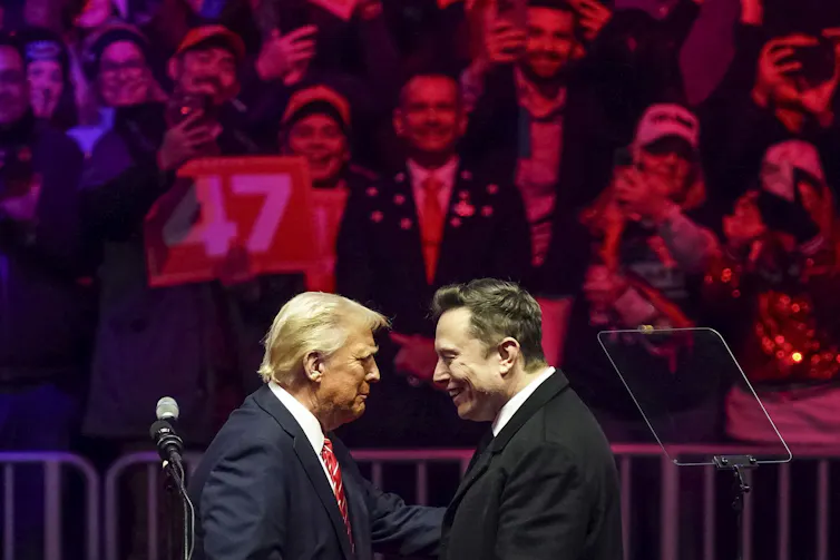 Musk and Trump embrace on stage during a rally.
