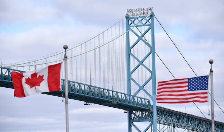 La bandera canadiense y la bandera de los Estados Unidos vuelan a ambos lados de un gran puente de acero