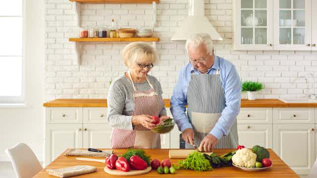 Happy senior couple making healthy lunch together in kitchen