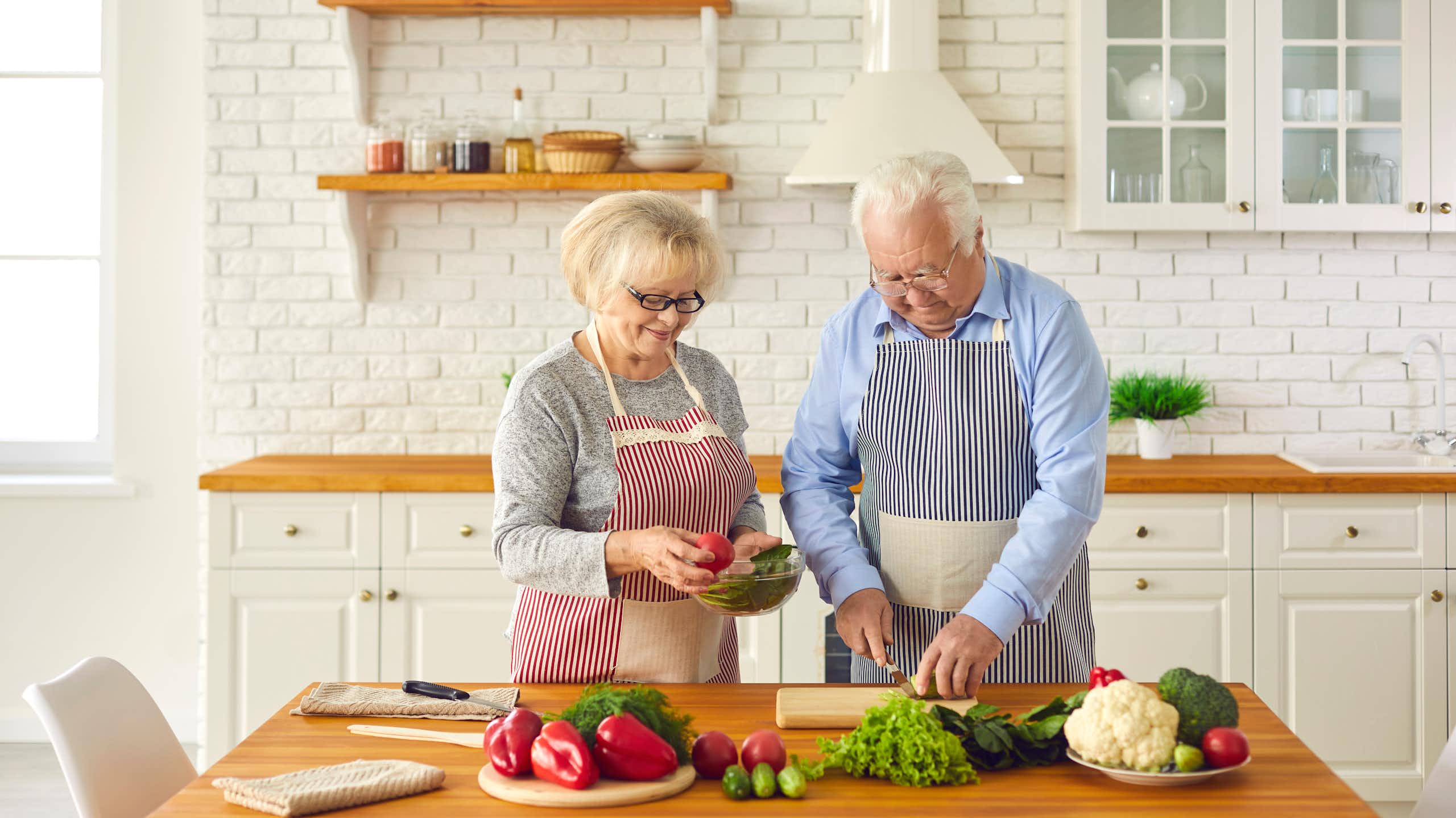 Happy senior couple making healthy lunch together in kitchen