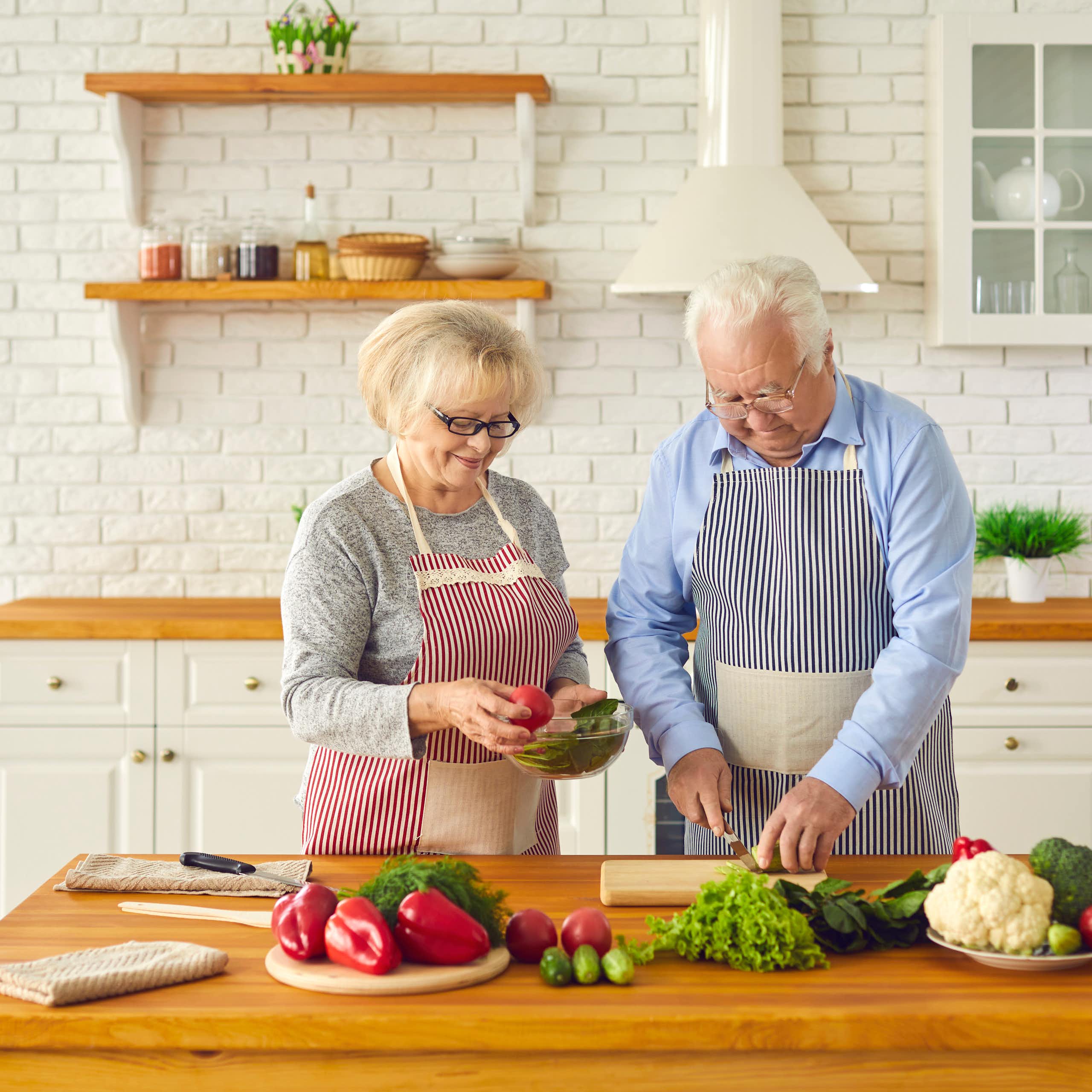 Happy senior couple making healthy lunch together in kitchen