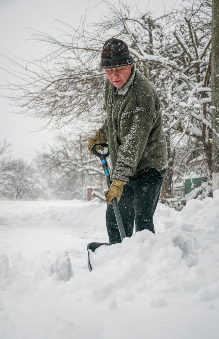 Un homme en train de pelleter de la neige