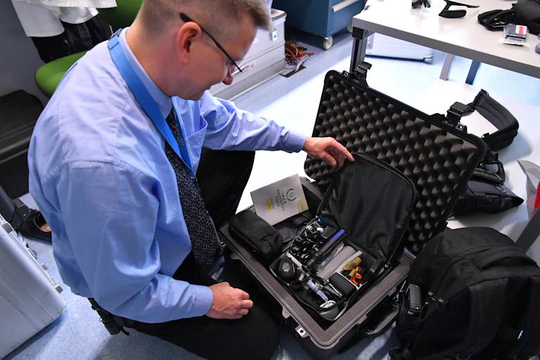 a man looks at a set off small devices inside a foam-lined travel case