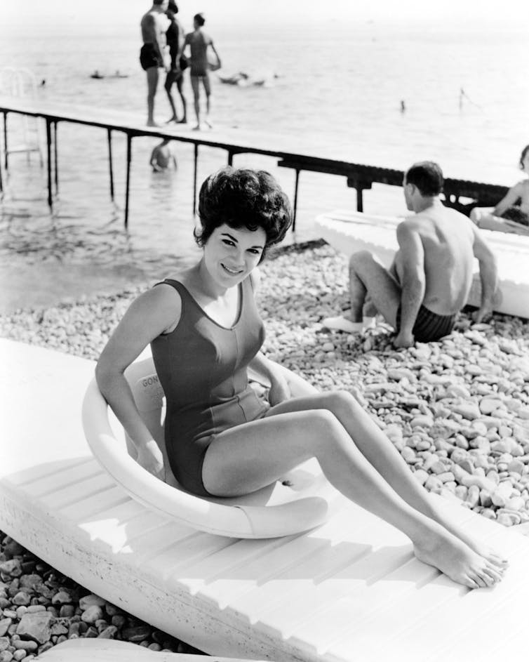 Francis sitting on a kayak in a one-piece swimsuit.