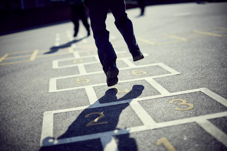 A child jumps on a hopscotch grid in a playground