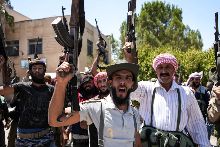 Armed bedouin fighters brandish their weapons for a photograph.