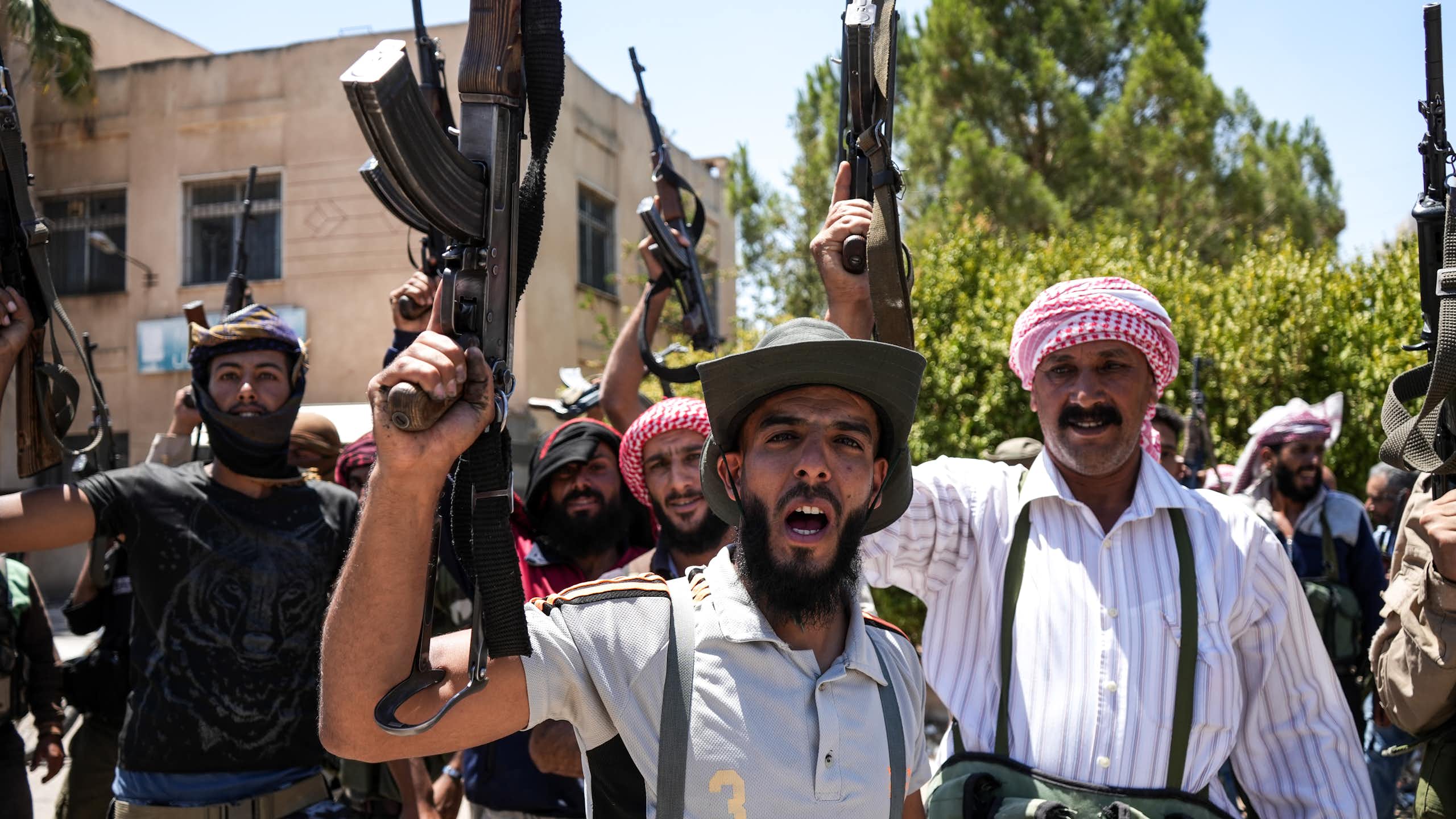 Armed bedouin fighters brandish their weapons for a photograph.