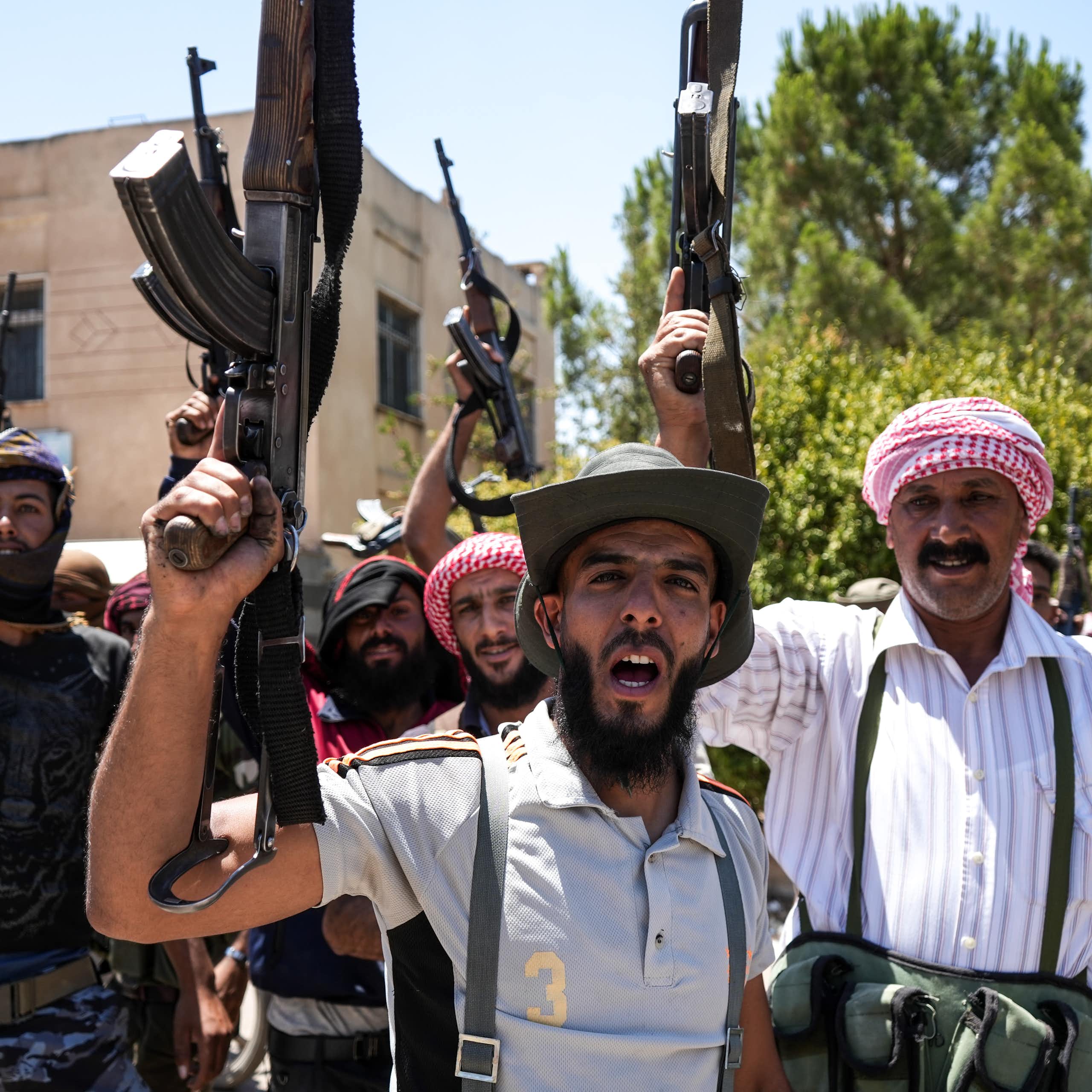 Armed bedouin fighters brandish their weapons for a photograph.