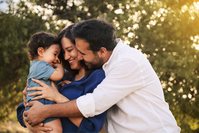 A mother, father and baby sharing joyful embrace outdoors