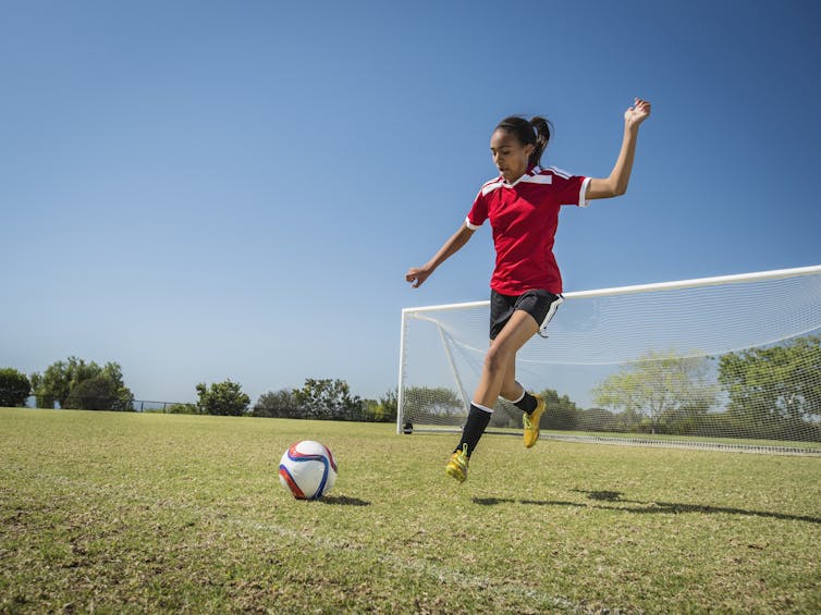 girl about to kick a soccer ball