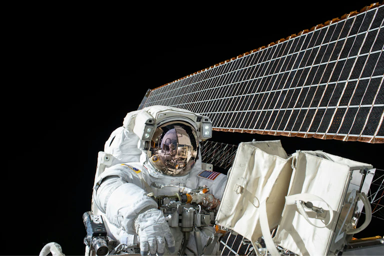 Astronaut walking in space next to photovoltaic panels