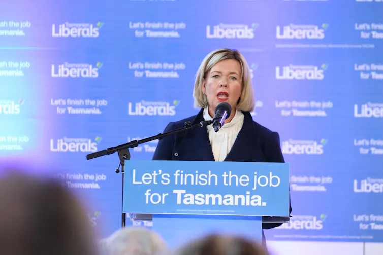 A woman speaks at a blue podium that says Let's finish the job for Tasmania