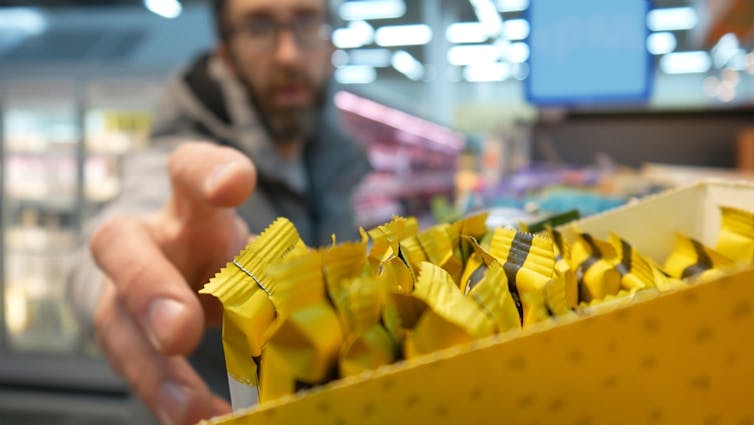 A man reaching for a protein bar in a shop.