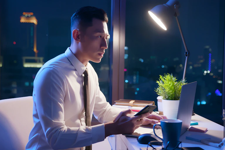 Man sitting at a desk, working on a computer, after dark