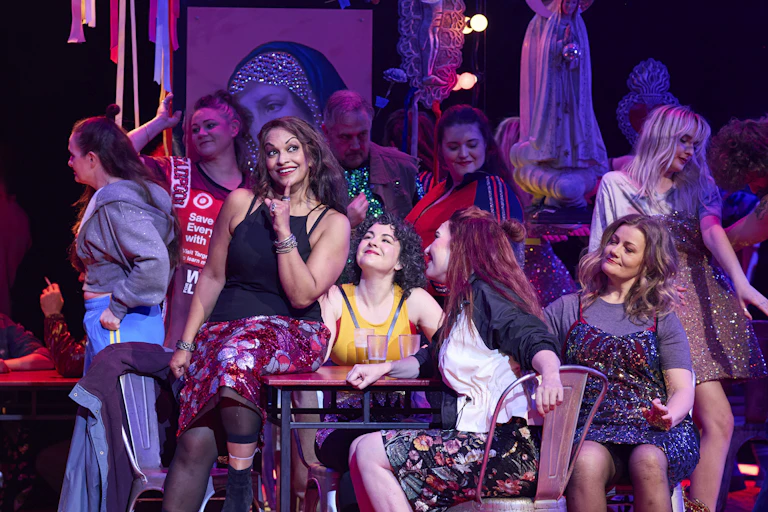 Production image: women sit together, maybe at a bar.
