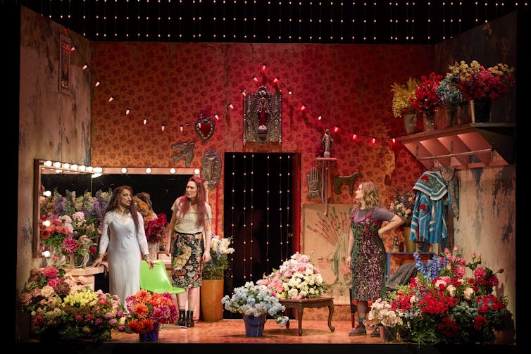 Production image: a dressing room filled with flowers.