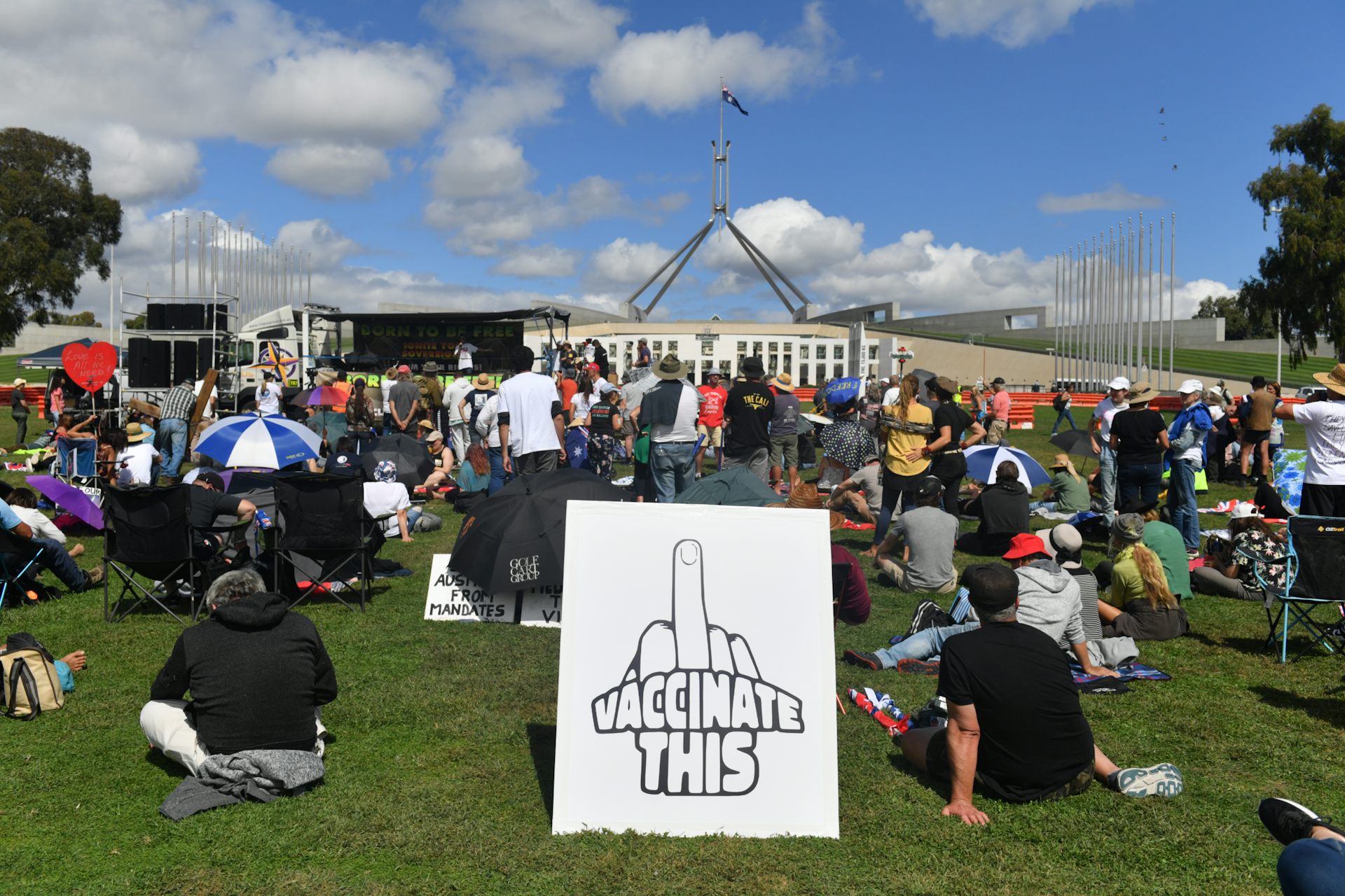 Protestors with a large sign depicting the middle finger outside Parliament House in Canberra.