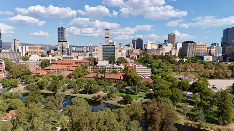 Aerial photo of Adelaide showing the tree-lined River Torrens, modern and heritage architecture, and the University of Adelaide City Camp