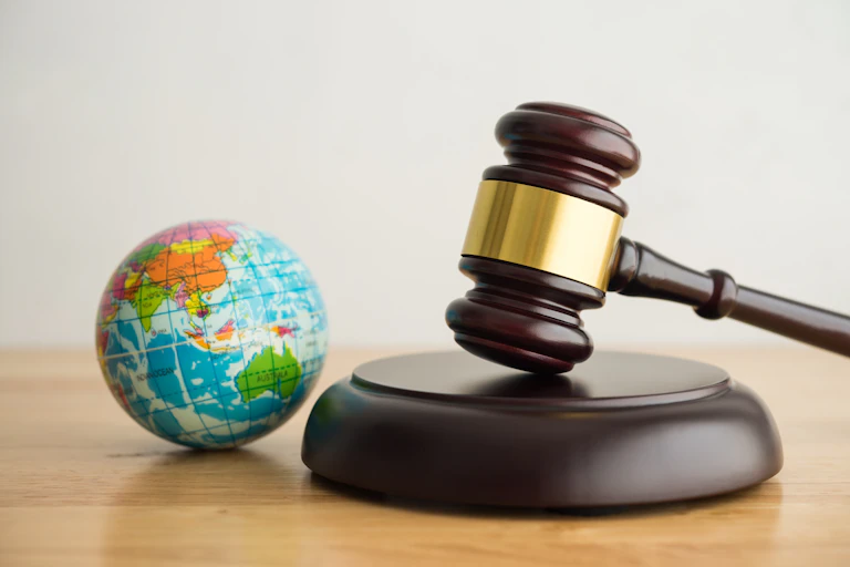 judge gavel on desk next to toy globe