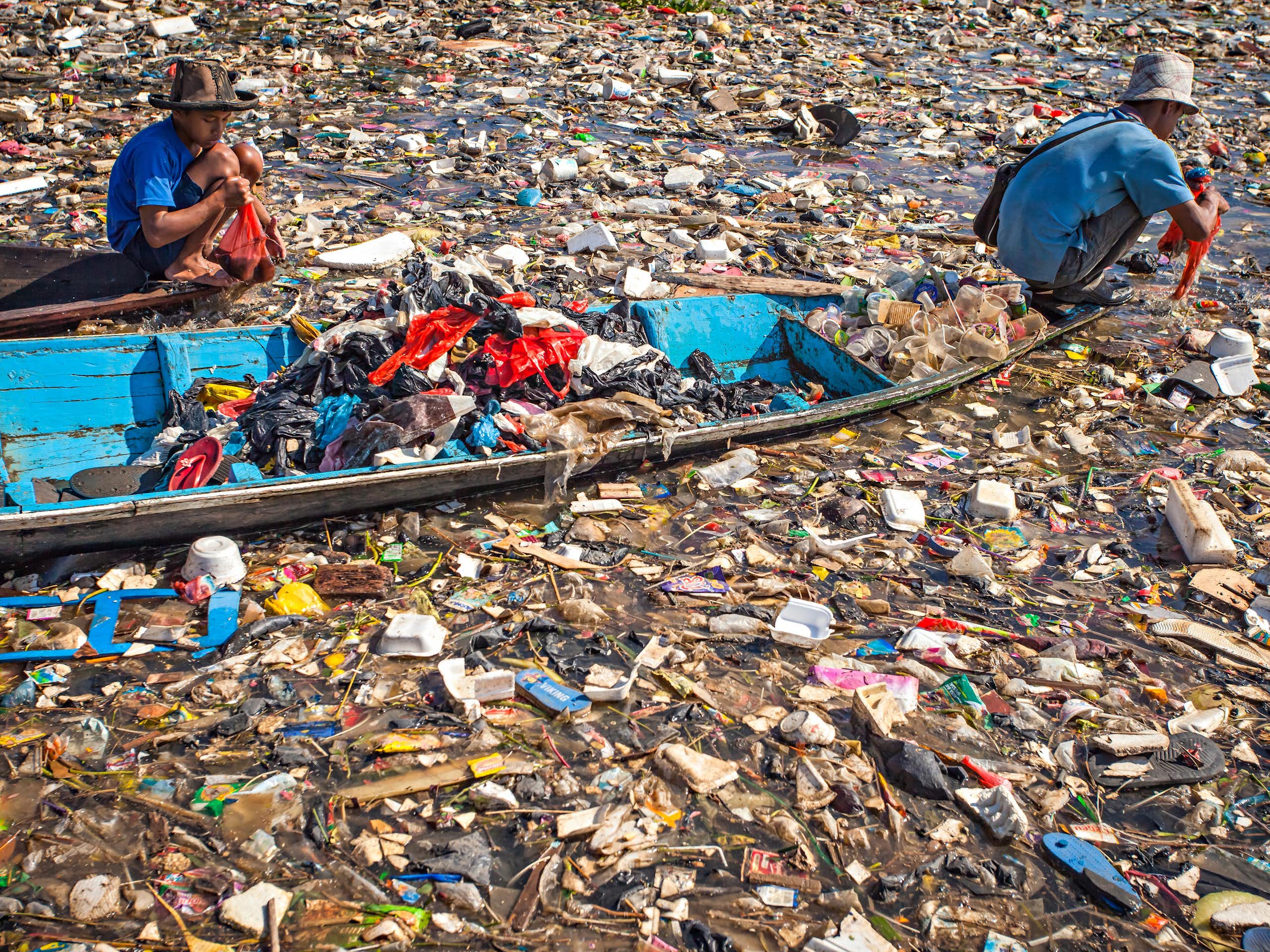 Two people ride a boat through heavily polluted water.