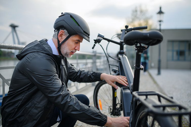 A man in a suit and helmet attending his e-bike.