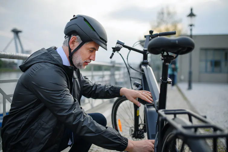 A man in a suit and helmet attending his e-bike.