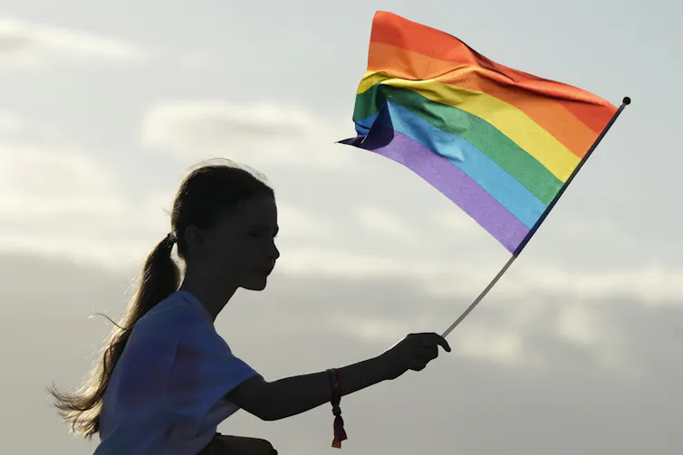 A girl waves a rainbow flag