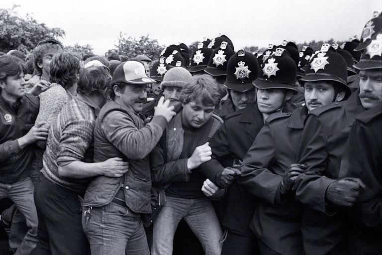 Black and white photo of a group of miners clashing against a wall of police