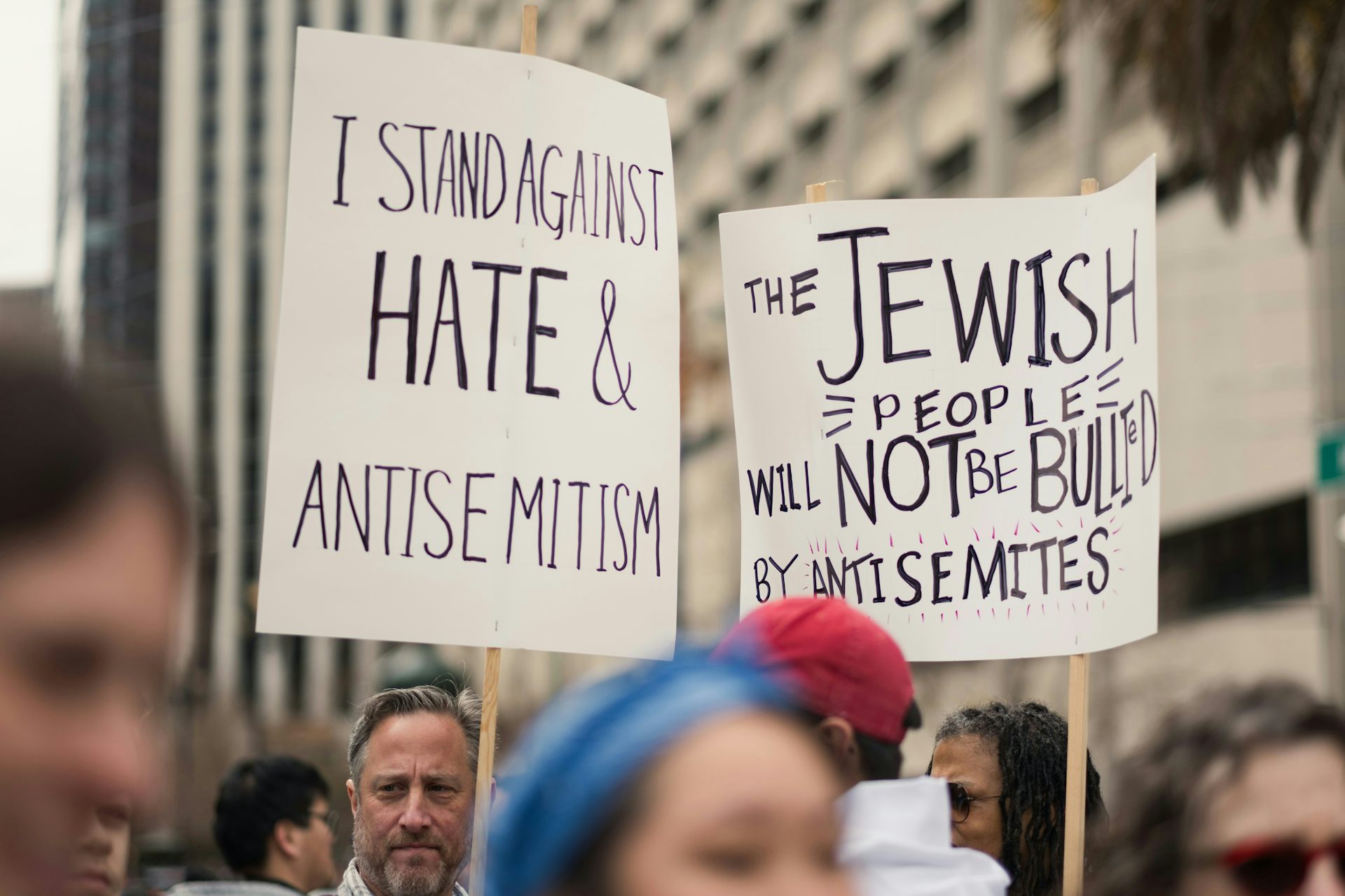 People stand with placards including one saying 'I stand against hate and antisemitism.'