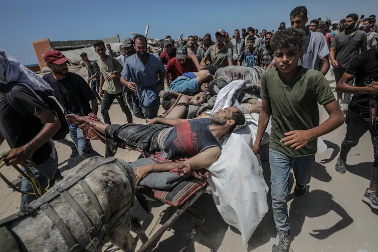 Dozens of people surrounding a man who was shot at an aid distribution point