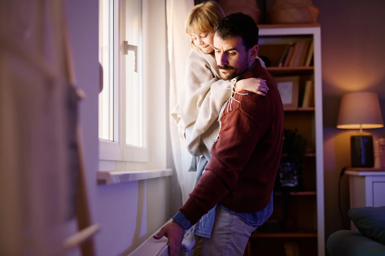 Father holding his daughter is checking the heating during an energy crisis.