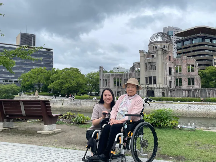 A Japanese woman pushing her grandmother in a wheelchair.