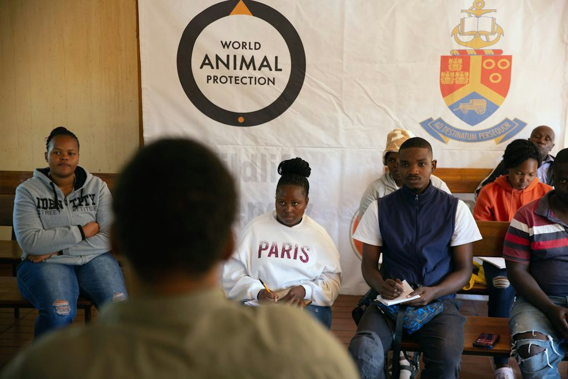 A group of people sit around under a banner that says World Animal Protection