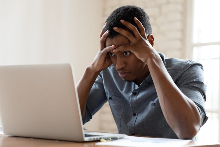 shocked man sitting staring at a laptop screen