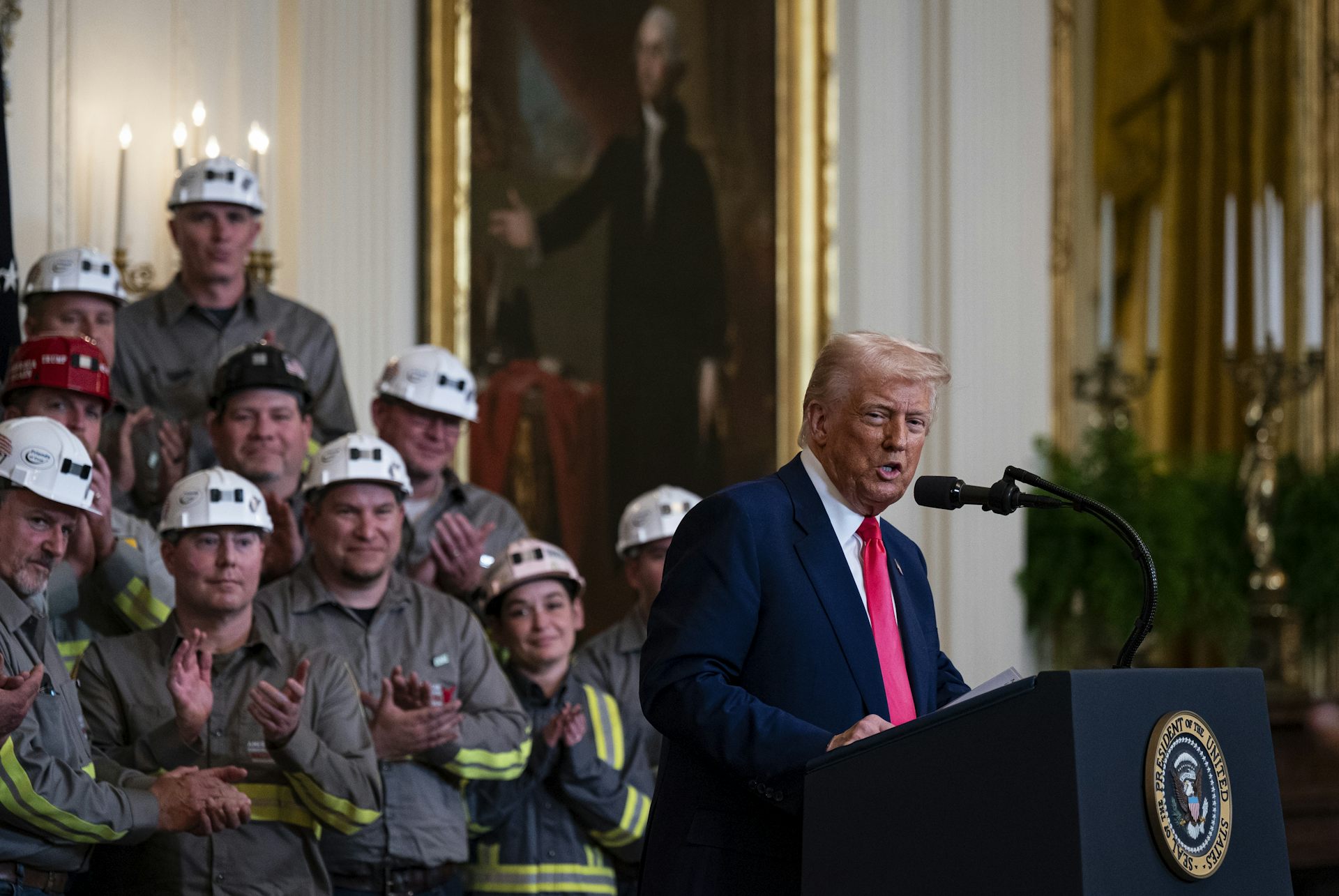 Trump, surrounded by coal-industry representatives, speaks after signing an executive order.
