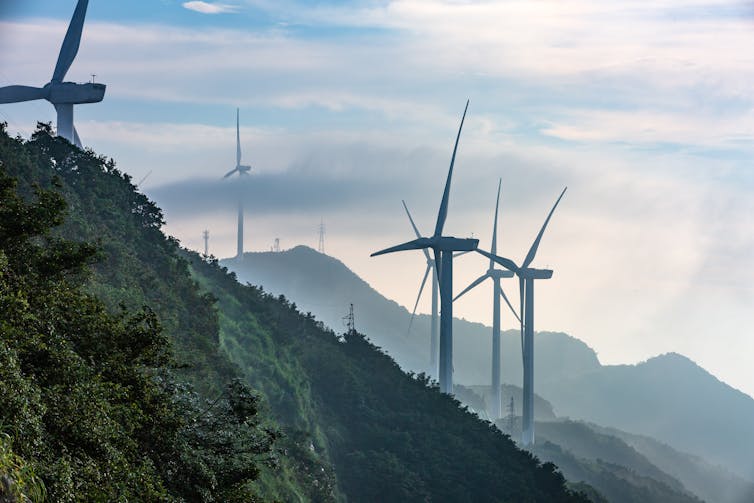 Wind turbines on top of green mountains.