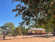 A small rectangular dwelling in barren land with a flimsy fence in front.
