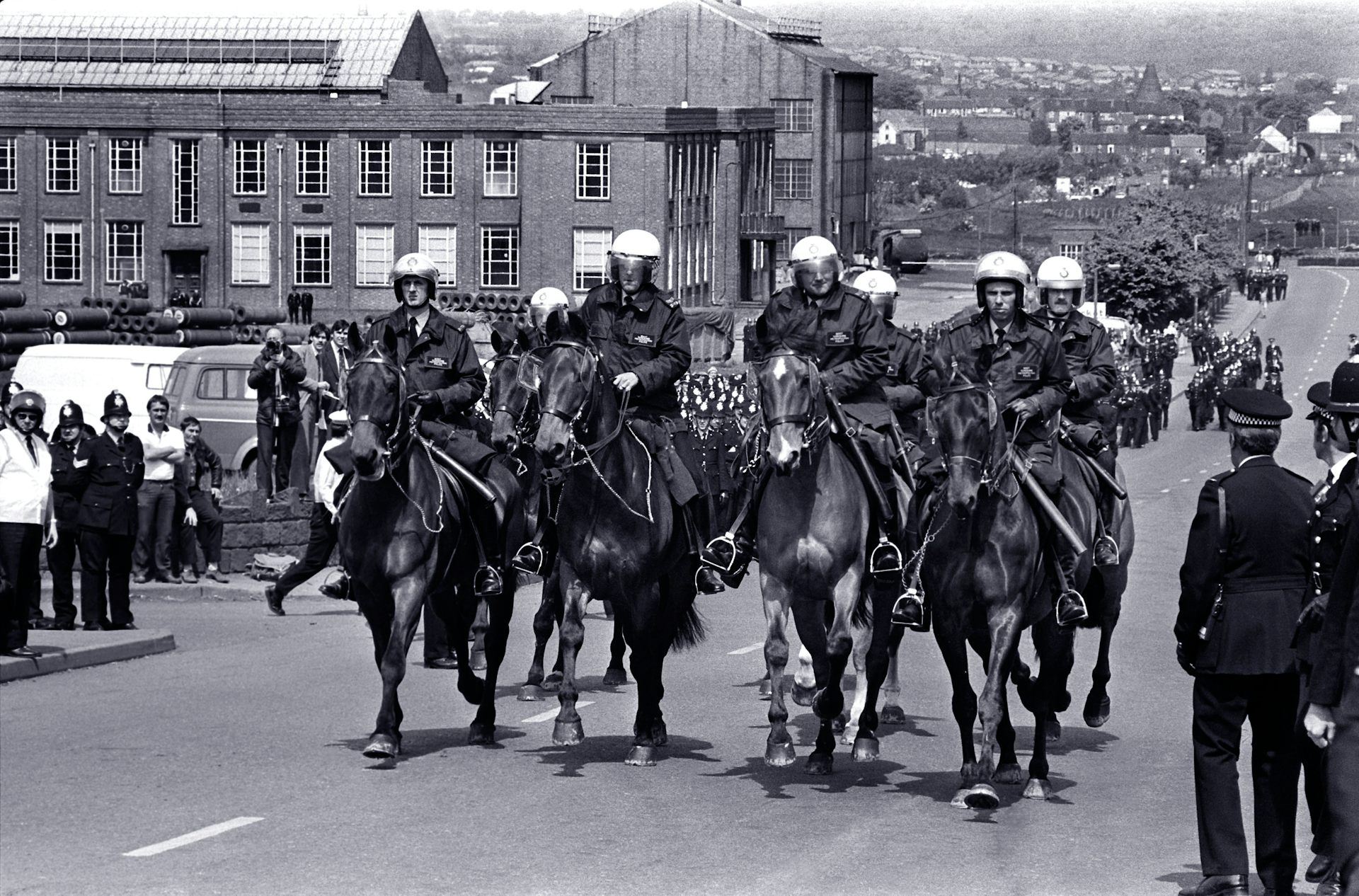 Black and white photo of a row of police on horseback