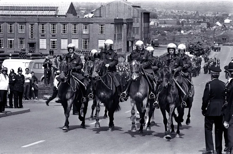 Black and white photo of a row of police on horseback
