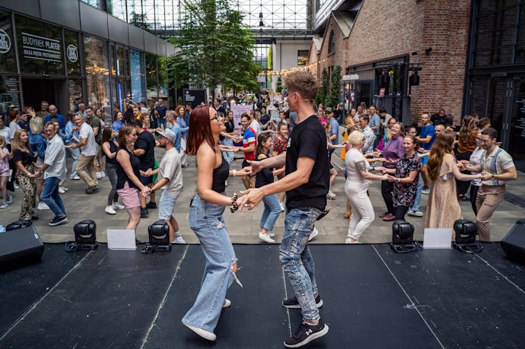 Couple leads a large crowd in a partner dance lesson