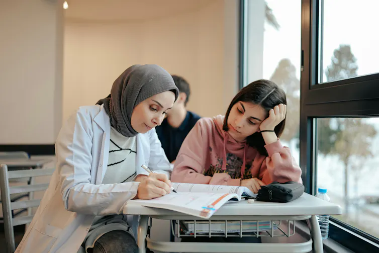 A teacher seated at a desk with a student.