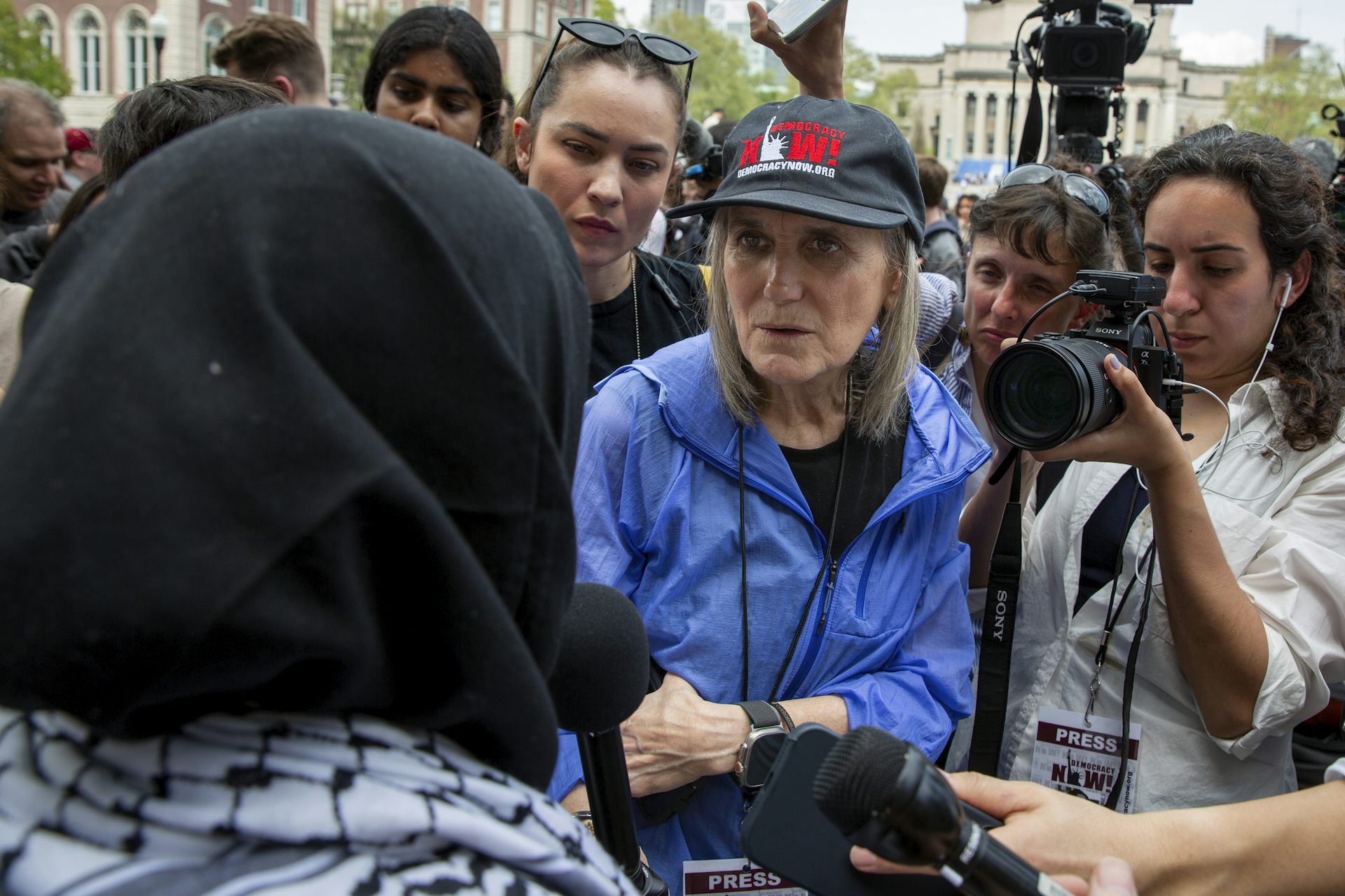 A woman in blue speaks to a woman wearing a black headscarf.