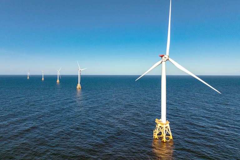 Several large-bladed turbines sit on posts above an expanse of water.