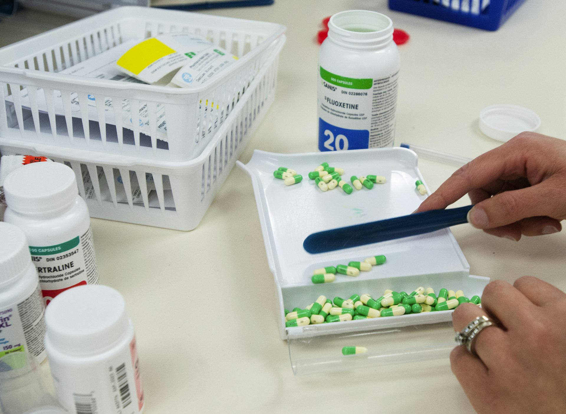Green and yellow capsules being counted out on a white pharmacist's tray