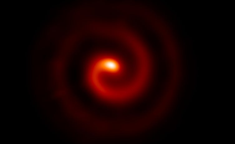 Një sfond i zi me një spirale të kuqe që rrotullohet në qendër që ndriçohet në një glob portokalli.