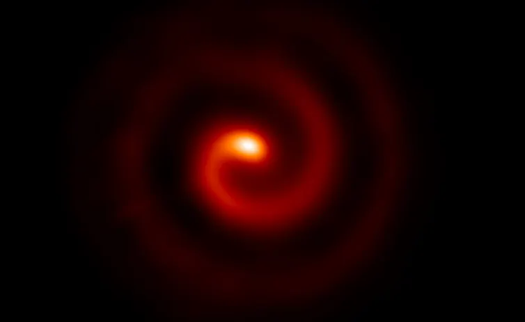 A black backfground with a swirling red spiral in the centre that brightens to an orange globe.