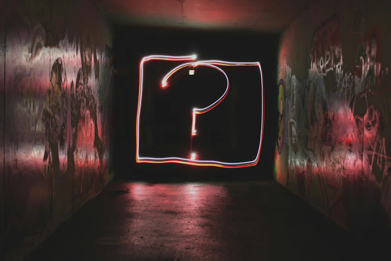 A long exposure photo of a question mark drawn with light in a moody underpass.