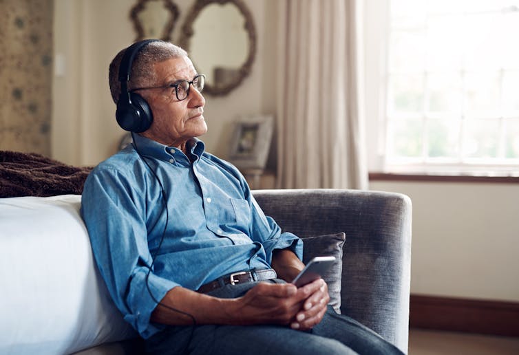 An older man listens to music with a wistful look on his face.